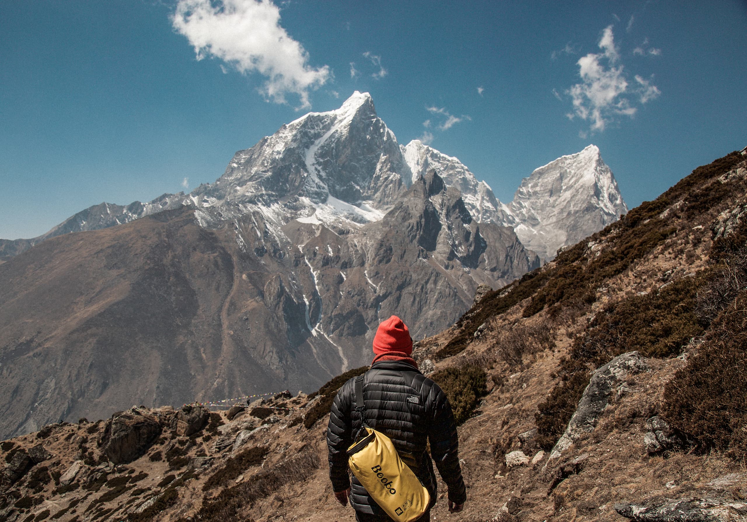 Man looking up at a tall mountain peak.