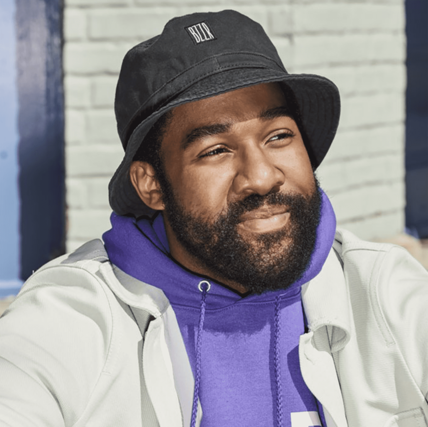 Happy man wearing a cotton bucket hat with a small square fabric logo stitched to the forehead