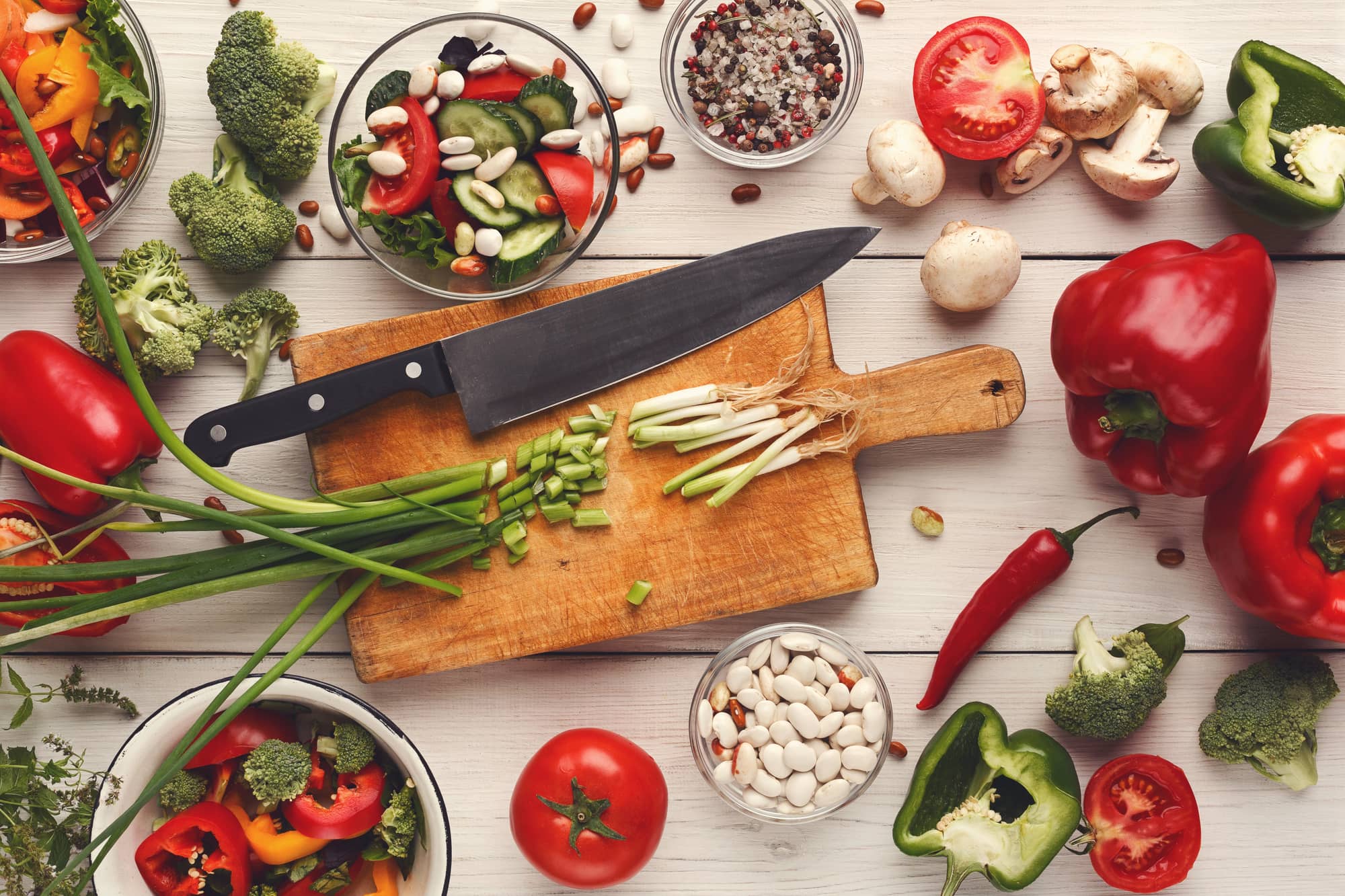 Assortment of vegetables surrounding a cutting board and knife