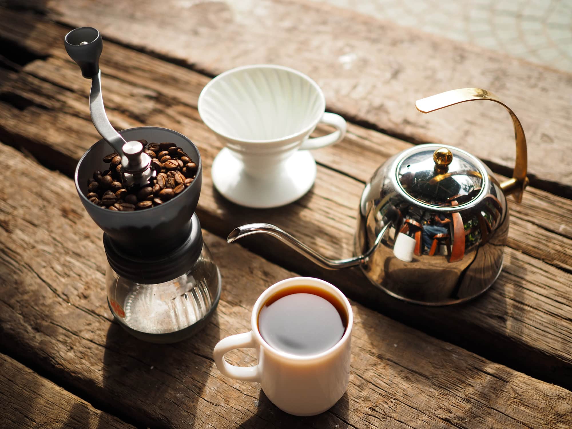 An assortment of coffee products, like a grinder, V60, pot and cup of coffee.