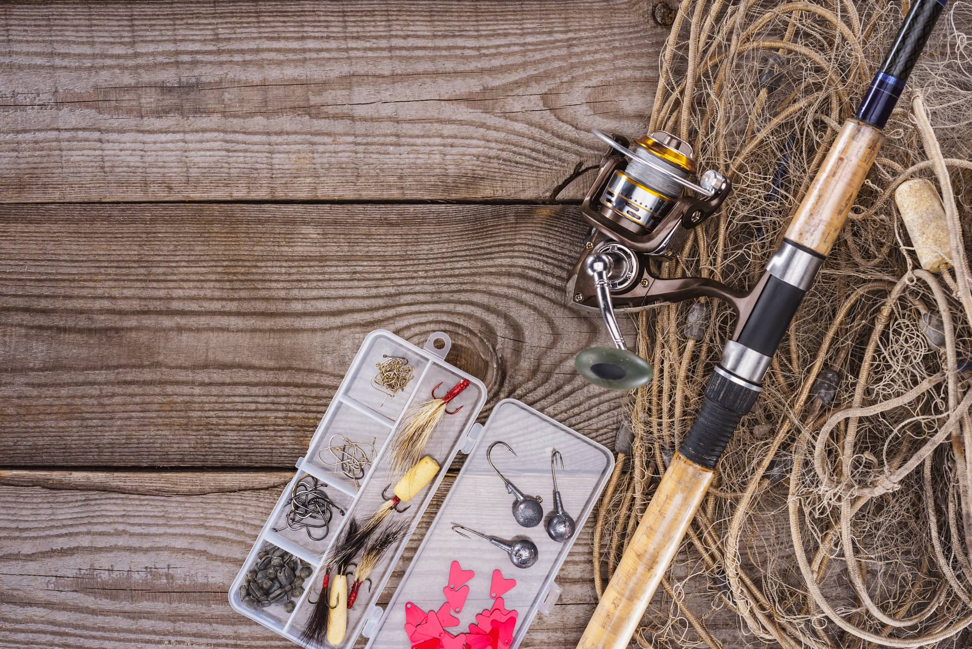 Flat lay with fishing net, fishing rod and plastic box with fishing accessories