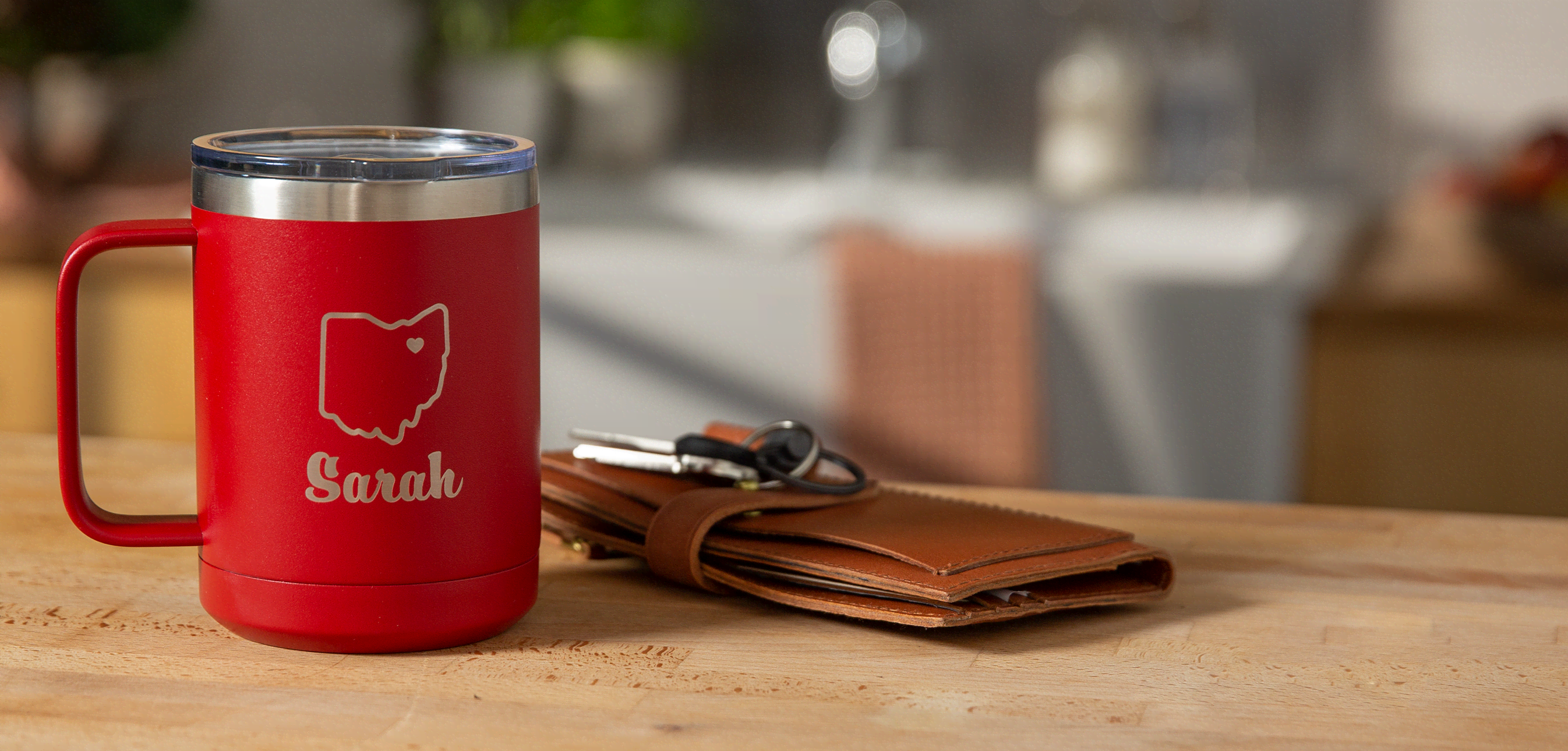 Custom travel mug in red with Ohio flag on it next to a wallet and keys graduation gift idea