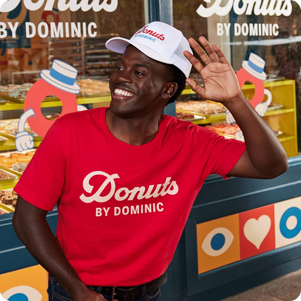 Man wearing branded merch for donut shop outside the shop.