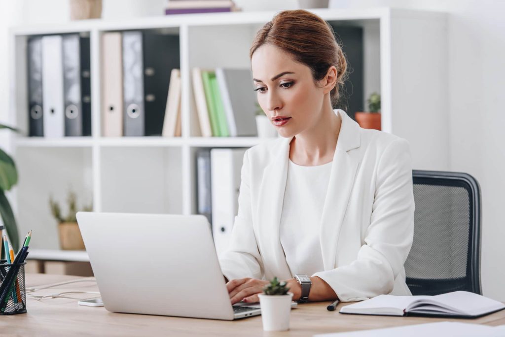 A woman works on a document on her laptop.