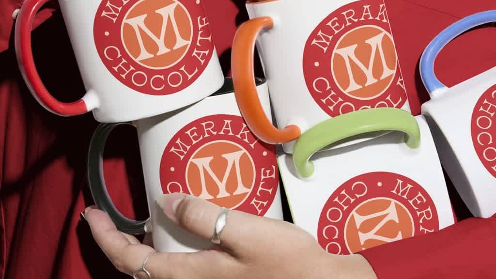 A person holding branded mugs with a business logo