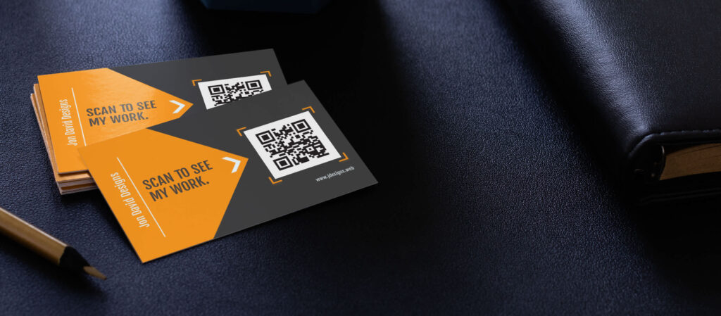 A stack of black and orange business cards with a QR code and a CTA “Scan to see my work