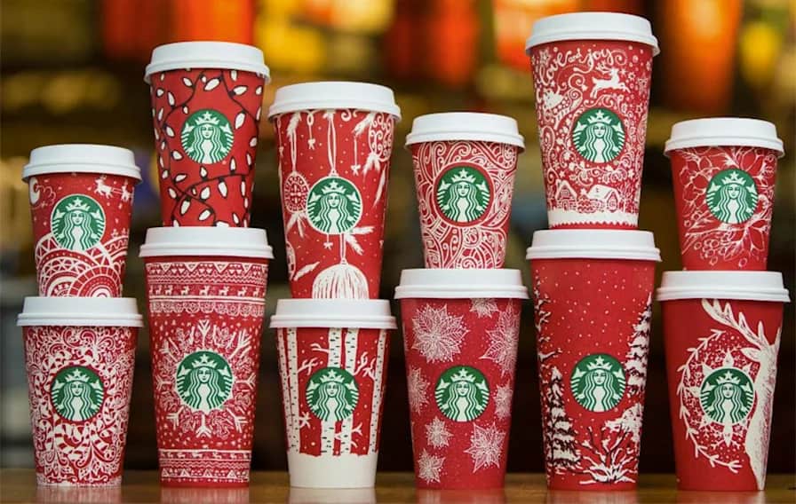 Lineup of festive Starbucks holiday cups in a variety of red and white winter themes