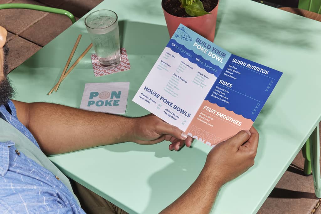 A person holding a bi-fold restaurant menu: How to design a menu