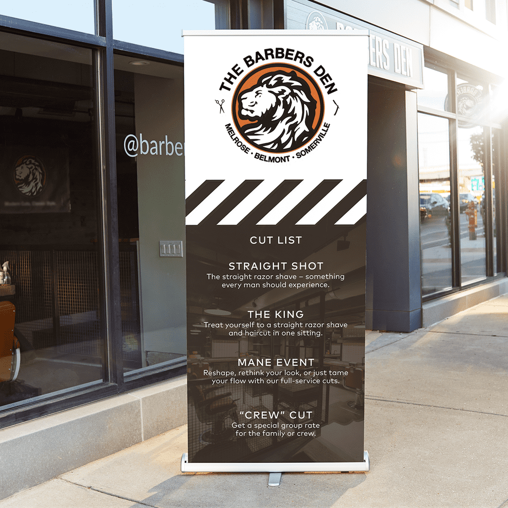 Retractable banner outside of barber shop with a haircut service list