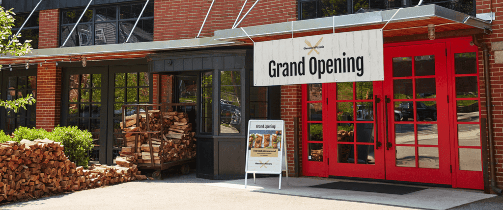 Example of grand opening signage in front of red doors with window panels.