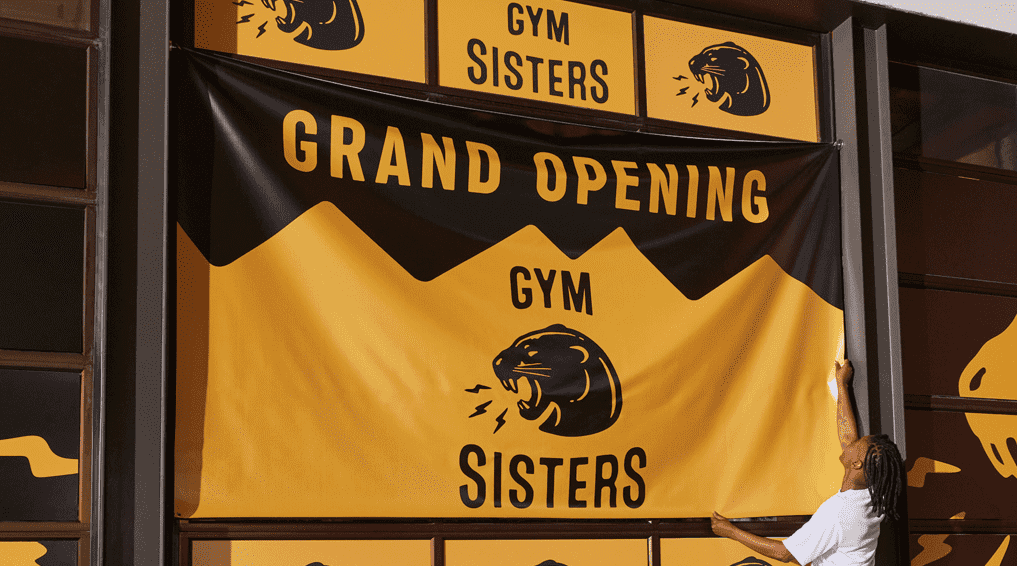 Grand opening Gym Sisters high contrast fabric banner hanging in window.