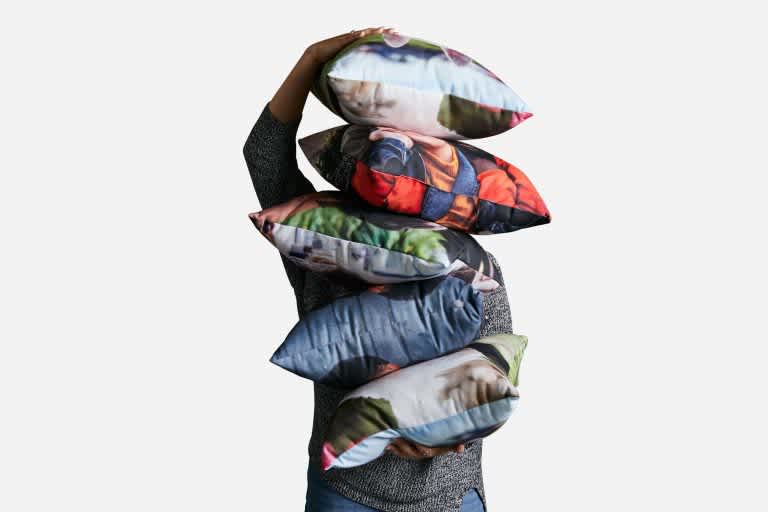 A man holding a stack of cushions.