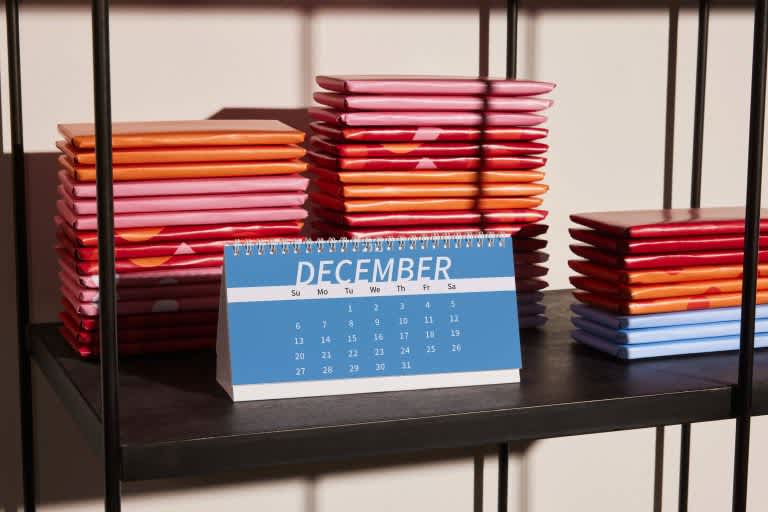 Small calendar on a shelf with notebooks.