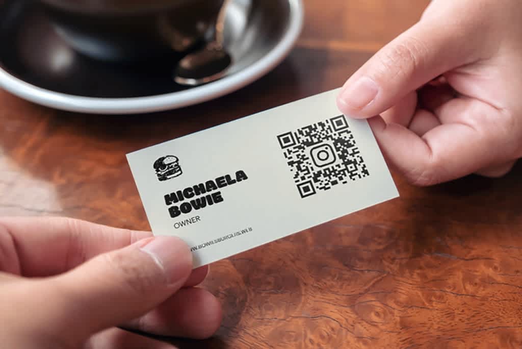 Simple white business card with small black burger logo, contact info and a large QR code in one half.