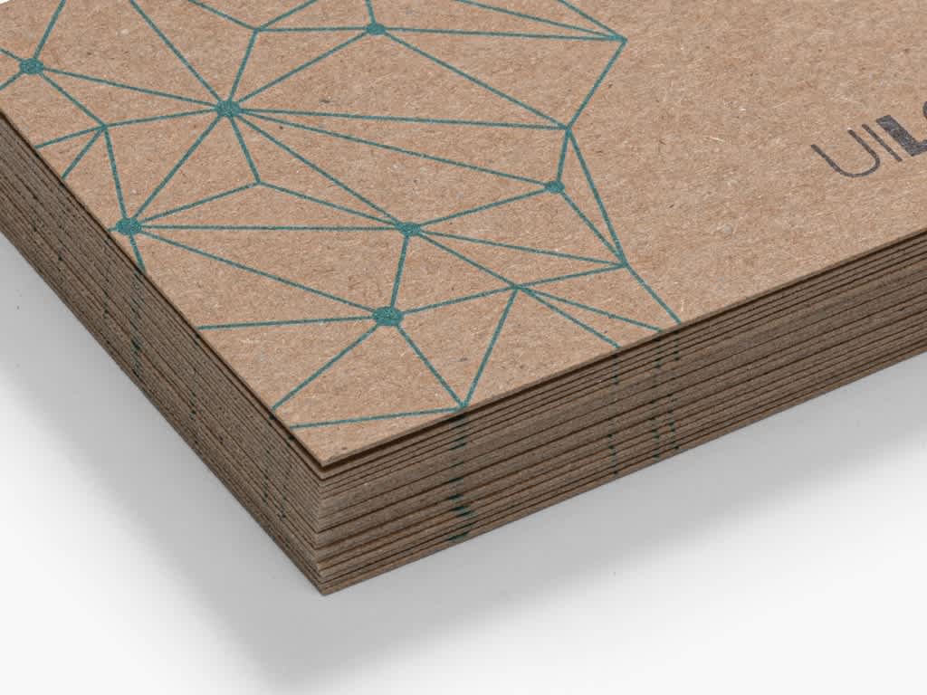 Close up of the corner of a stack of brown kraft paper stock business cards with turquoise geometric pattern.