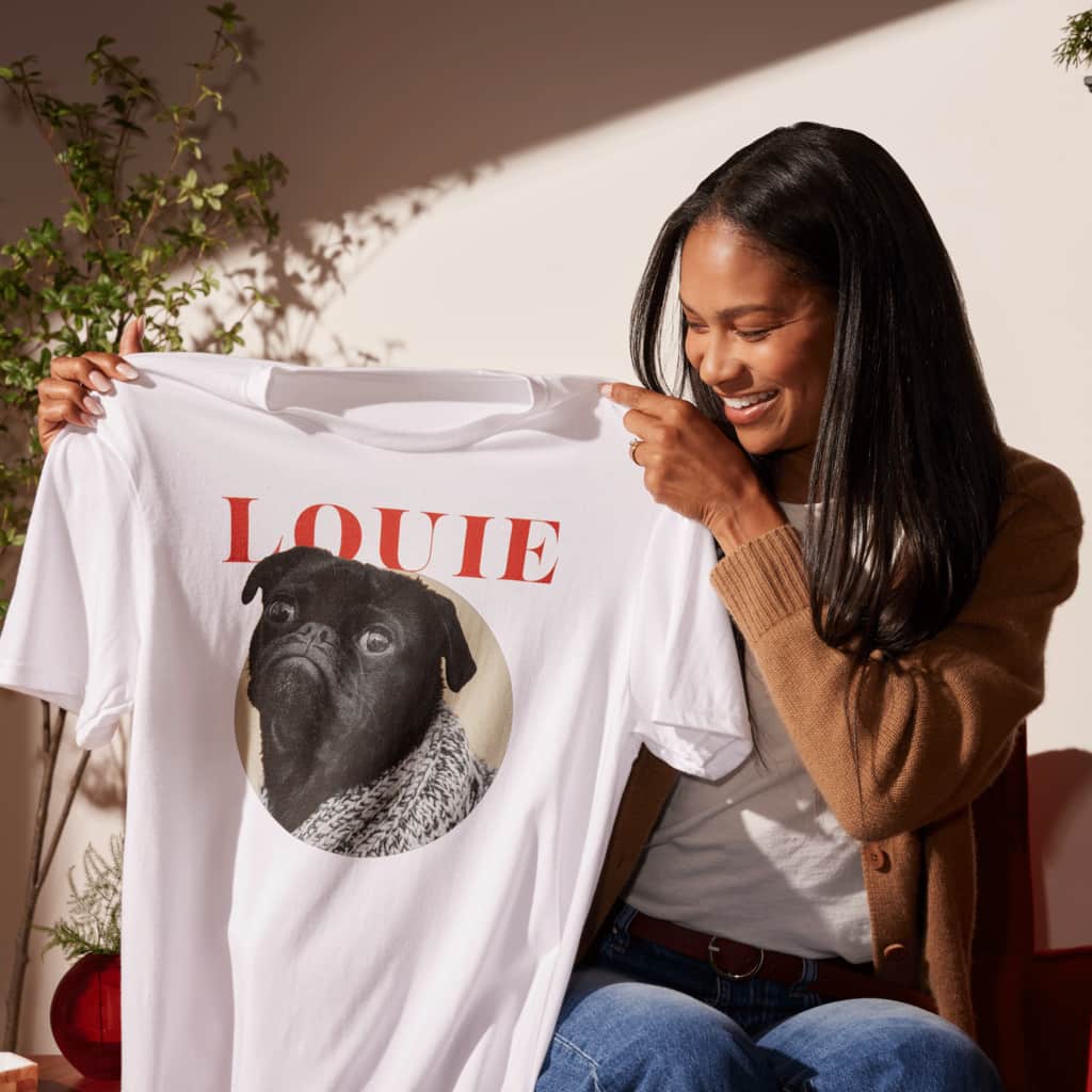 A woman holding a custom T-shirt with an image of dog.